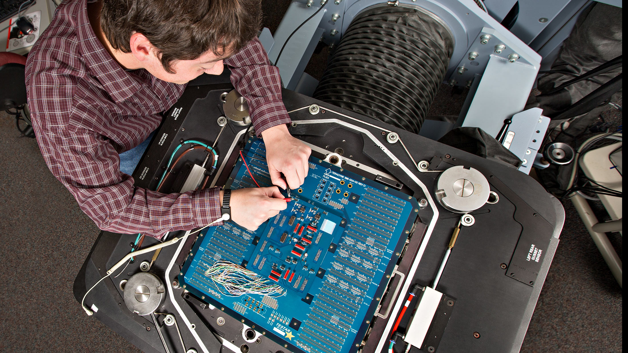 A person is working on a blue circuit board.