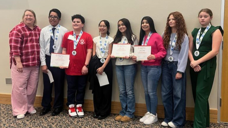 A female teacher with a group of middle school students.