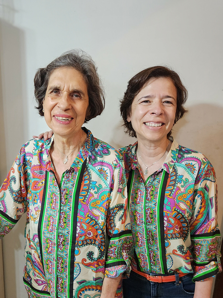 Two women smiling and standing together in matching patterned shirts.
