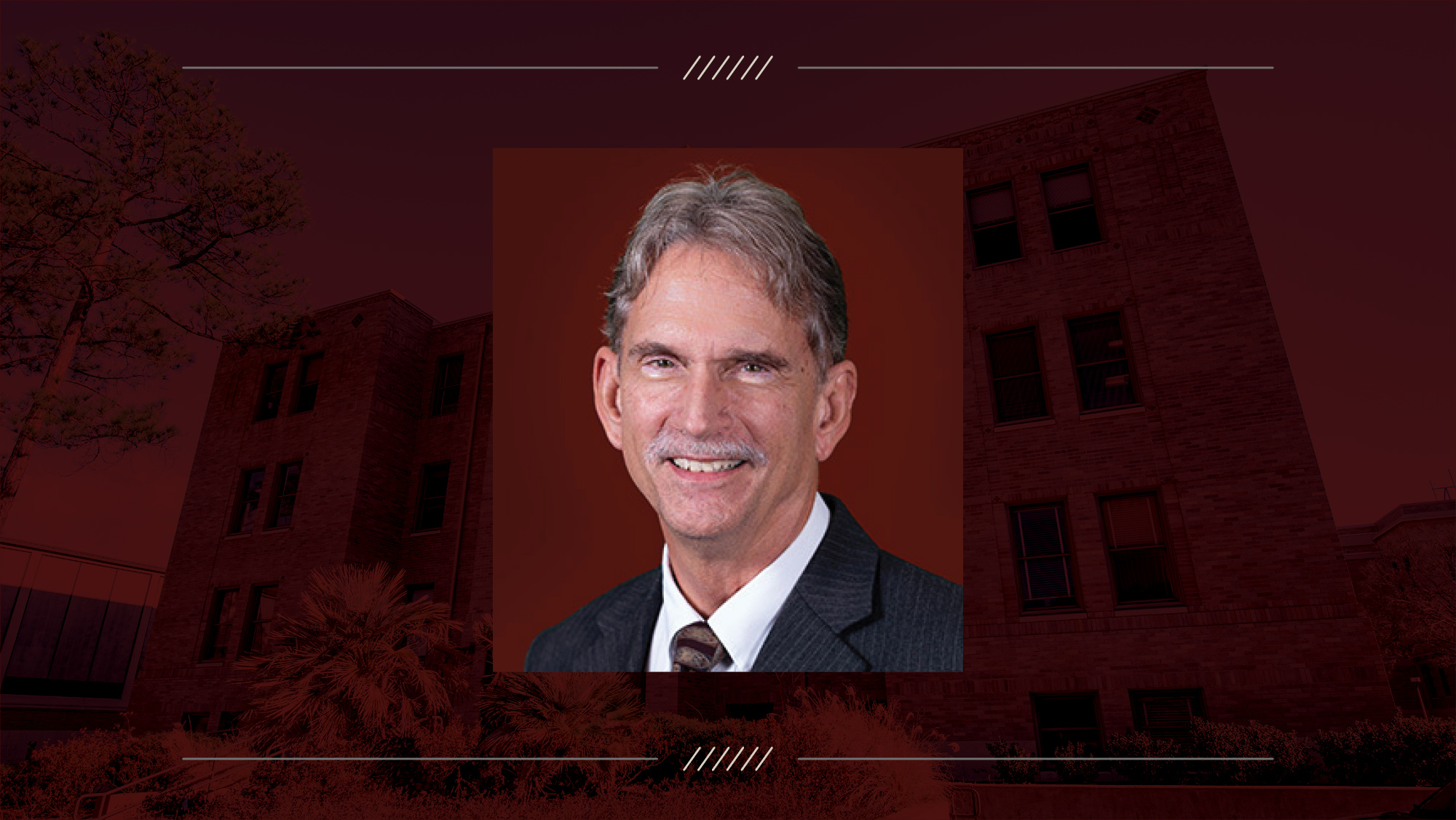Headshot of a man on a maroon background.