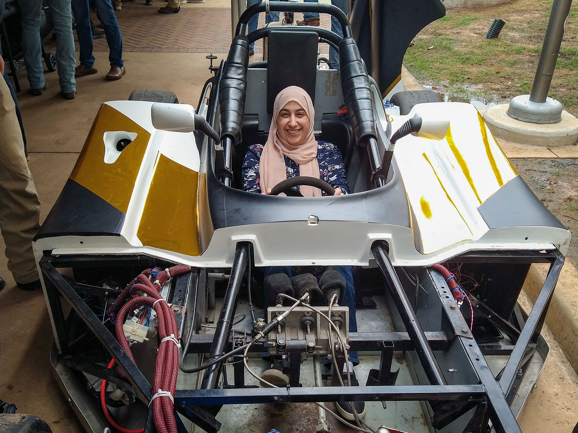 A woman smiles while sitting in a race car.