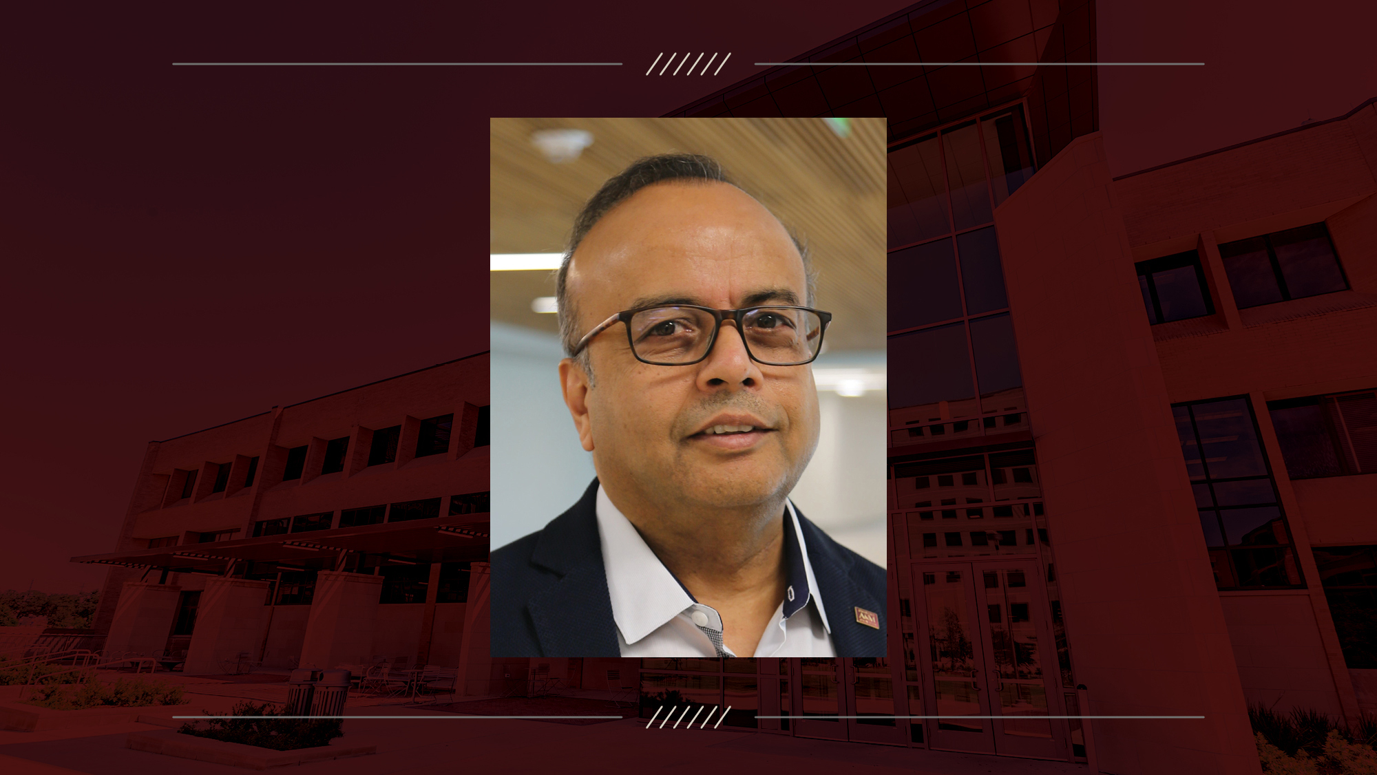 Man with glasses stands and smiles.