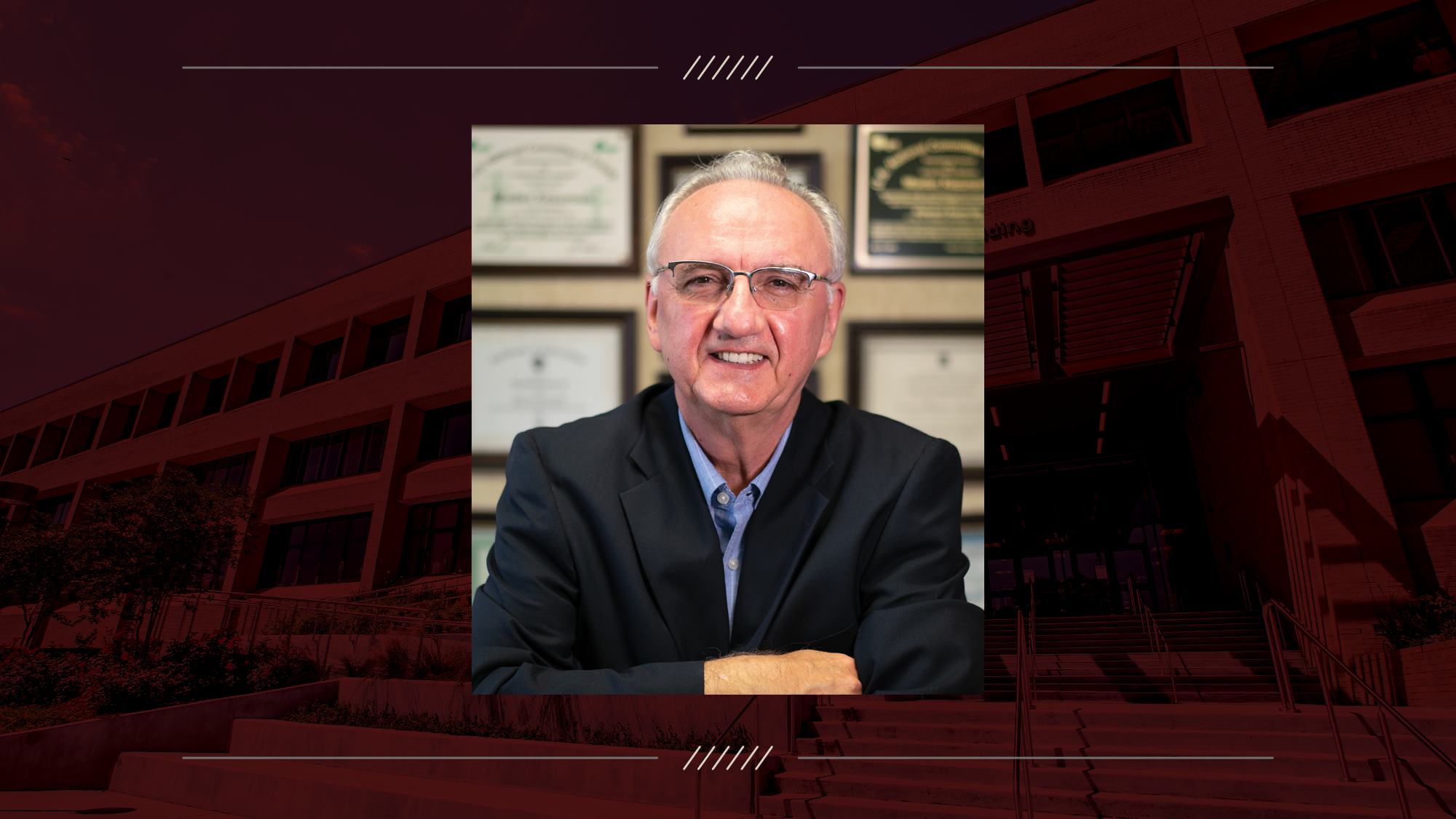 A man standing with his arms crossed in front of a wall of awards.