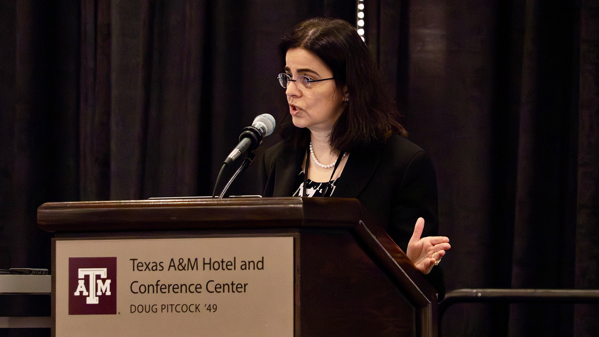 A woman speaks at a podium during an event at the Texas A&amp;M Hotel and Conference Center. 