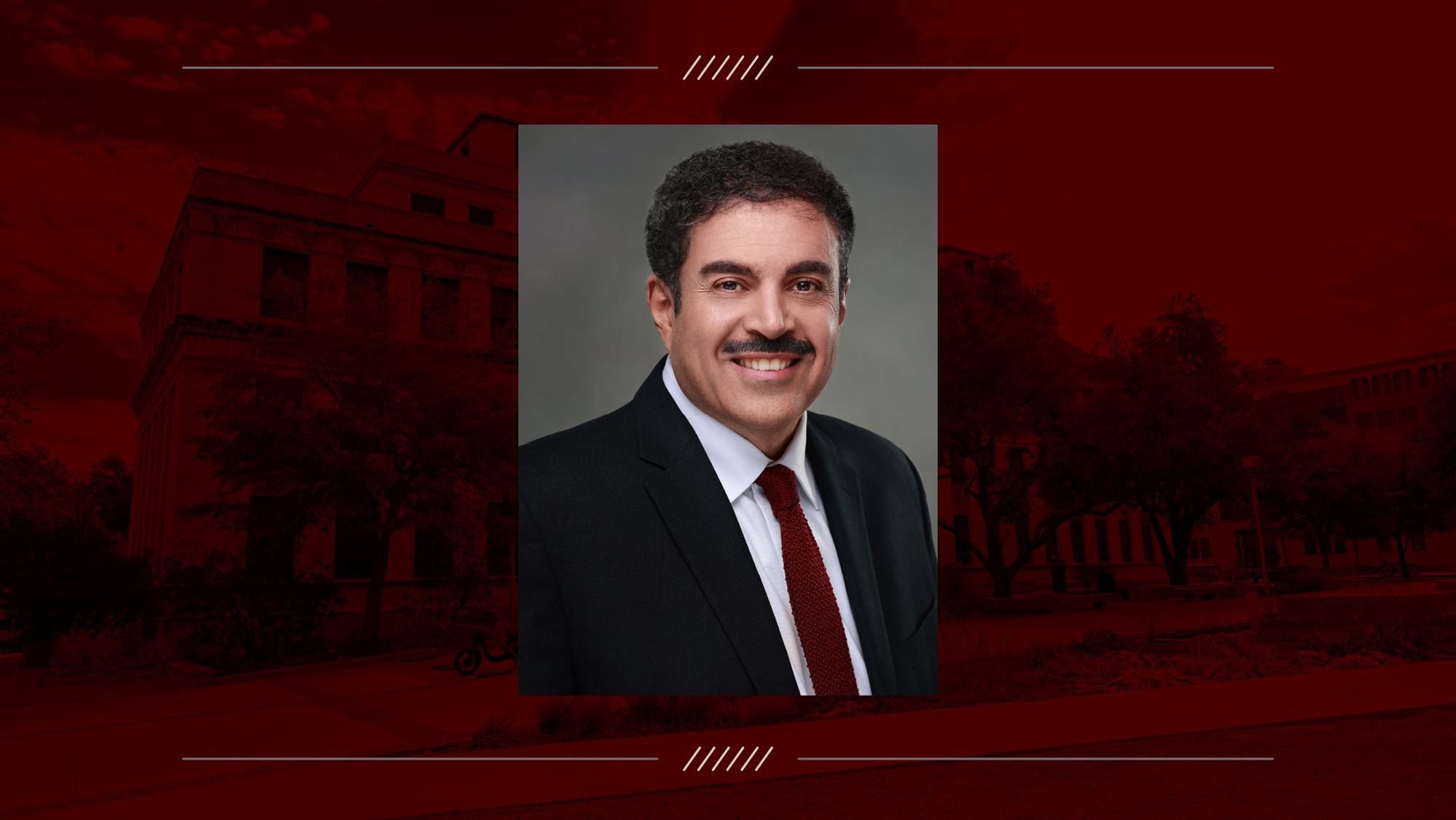 Headshot of a man on a maroon backgroound.