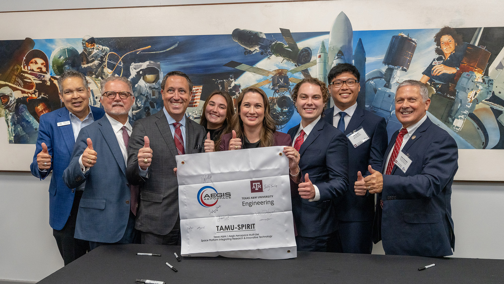 A group of Texas A&M, NASA and Aegis Aerospace officials pose for a photo.