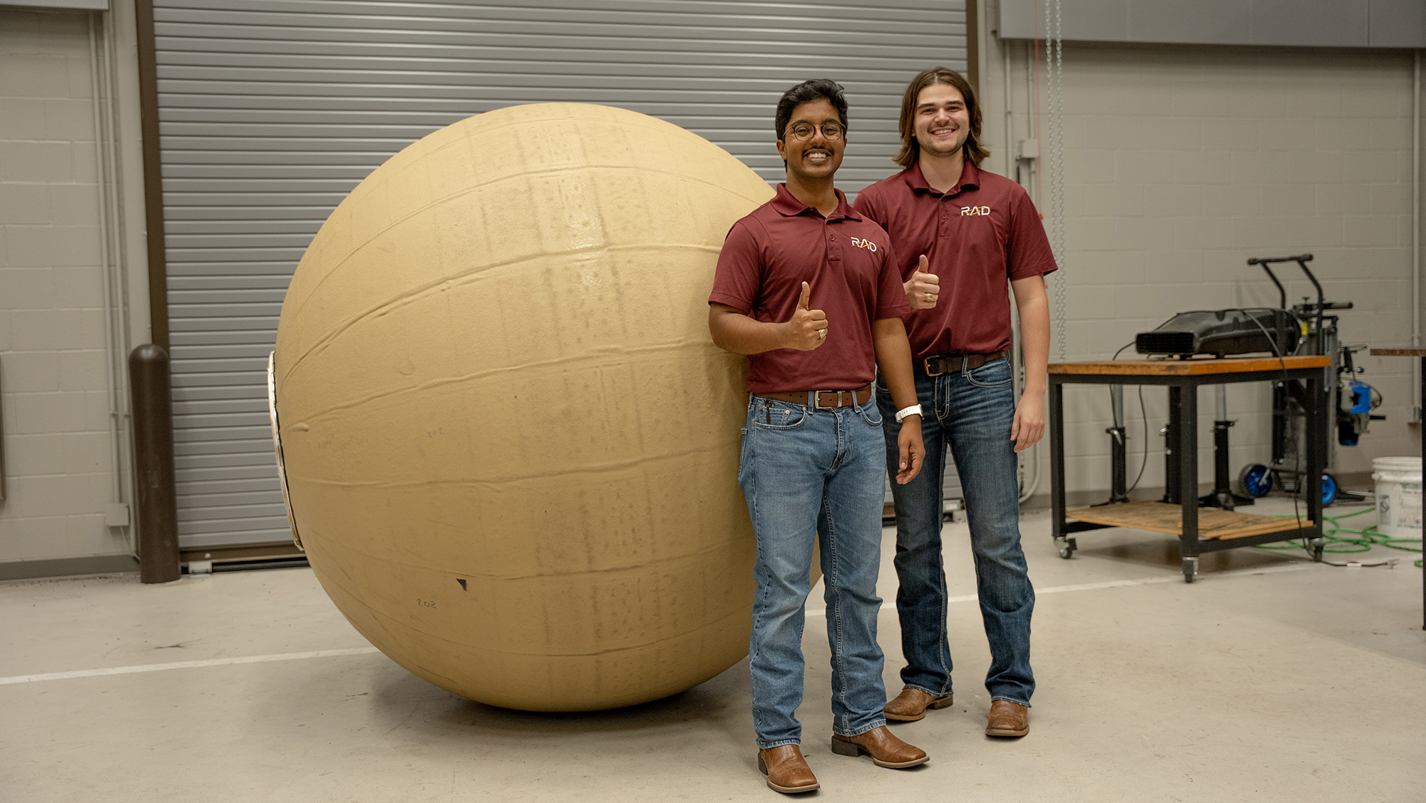 Men standing next to a large ball.