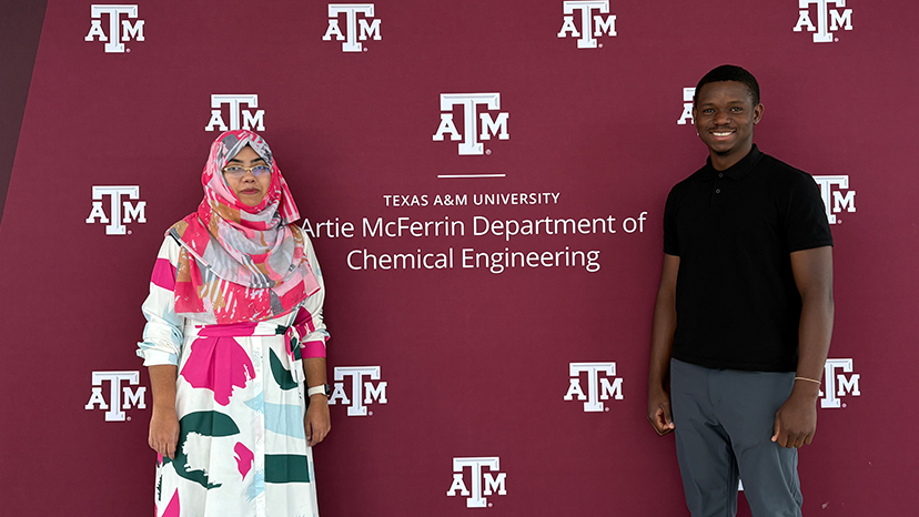 Two individuals stand in front of a backdrop promoting the Artie McFerrin Department of Chemical Engineering at Texas A&M University.