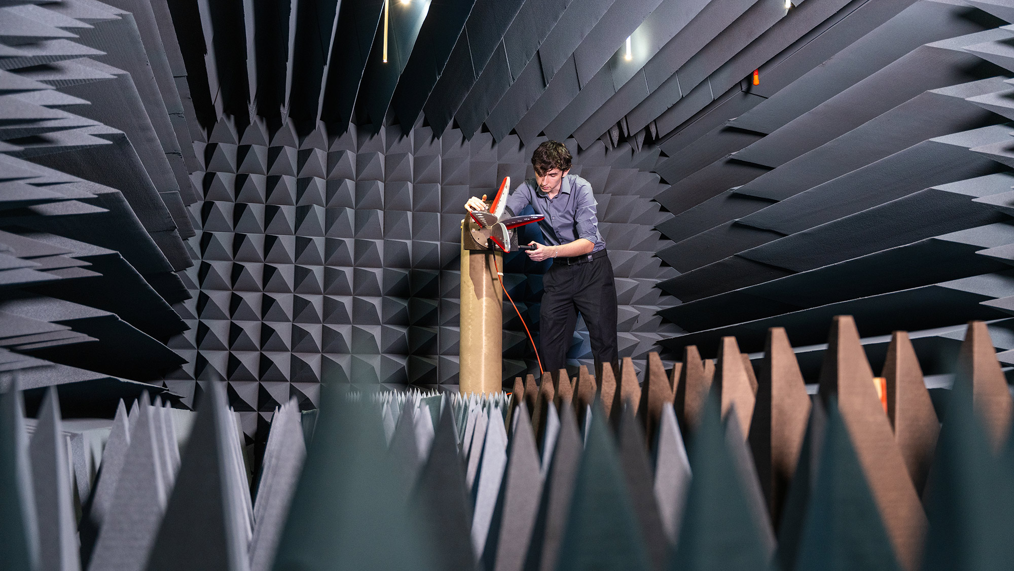 Person in a lab chamber surrounded by blue foam pyramids. 