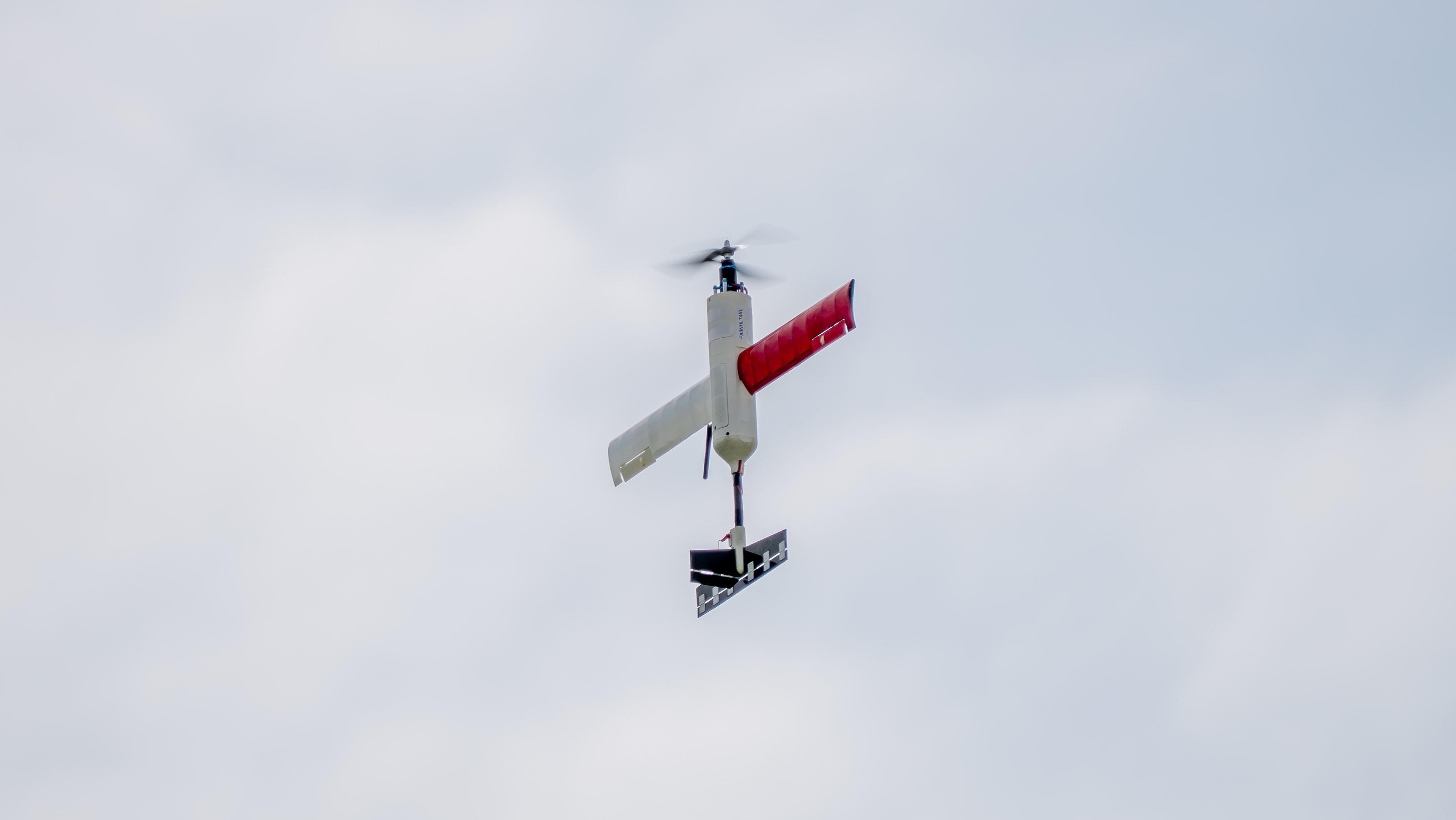 A small UAV flying upwards in the sky.