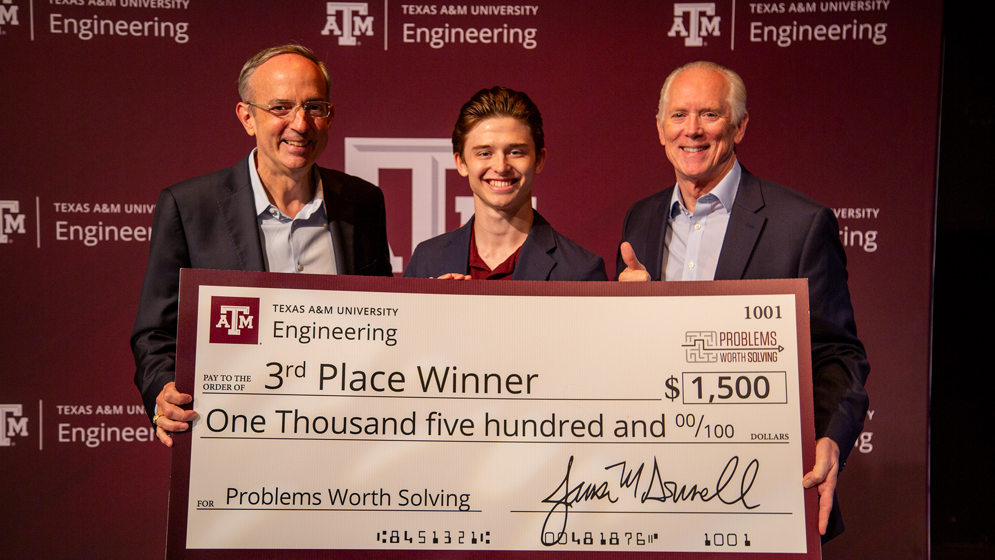 Three people smiling with an oversized check.