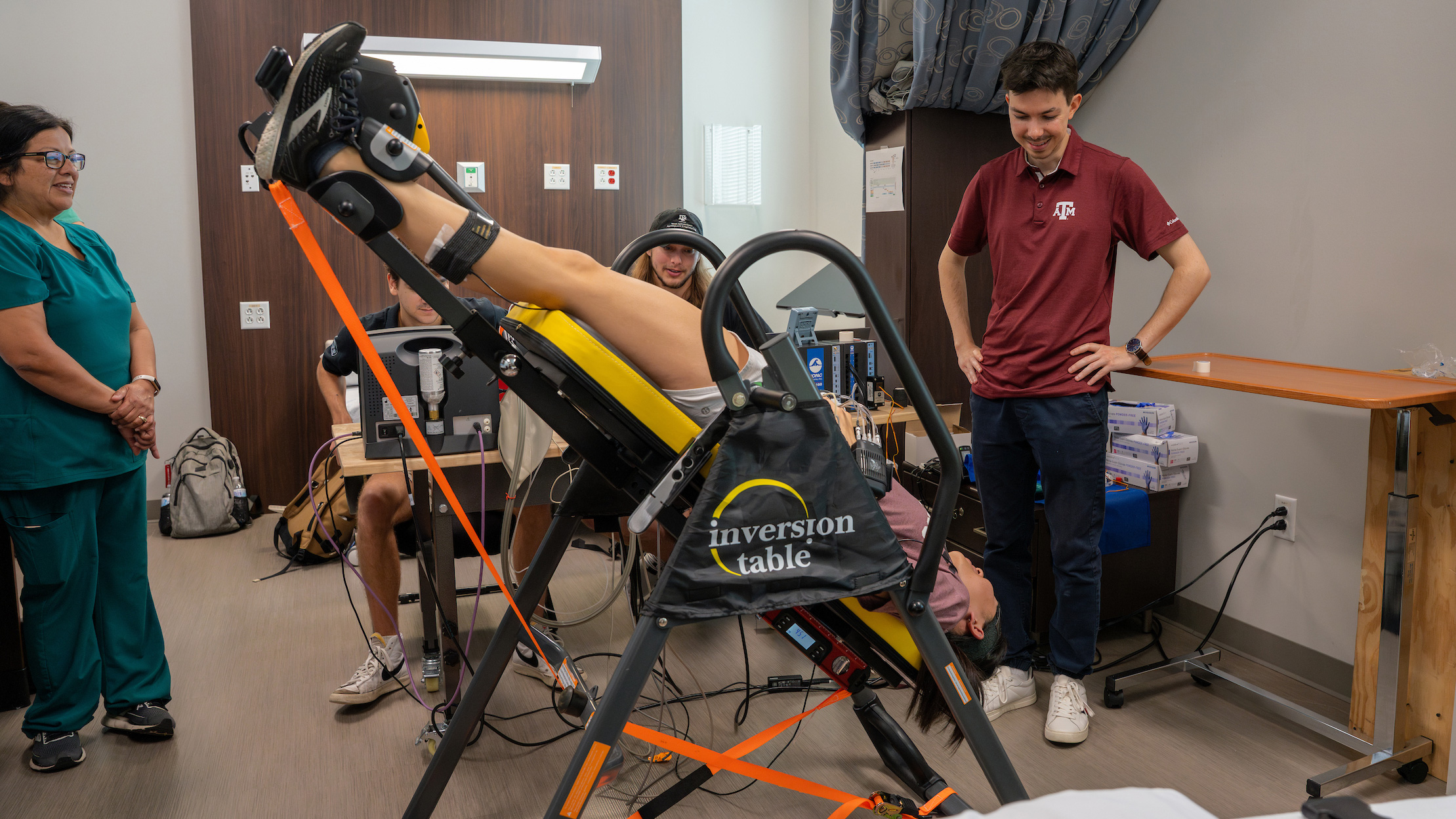 A study participant lying in a head down position next to standing researchers.