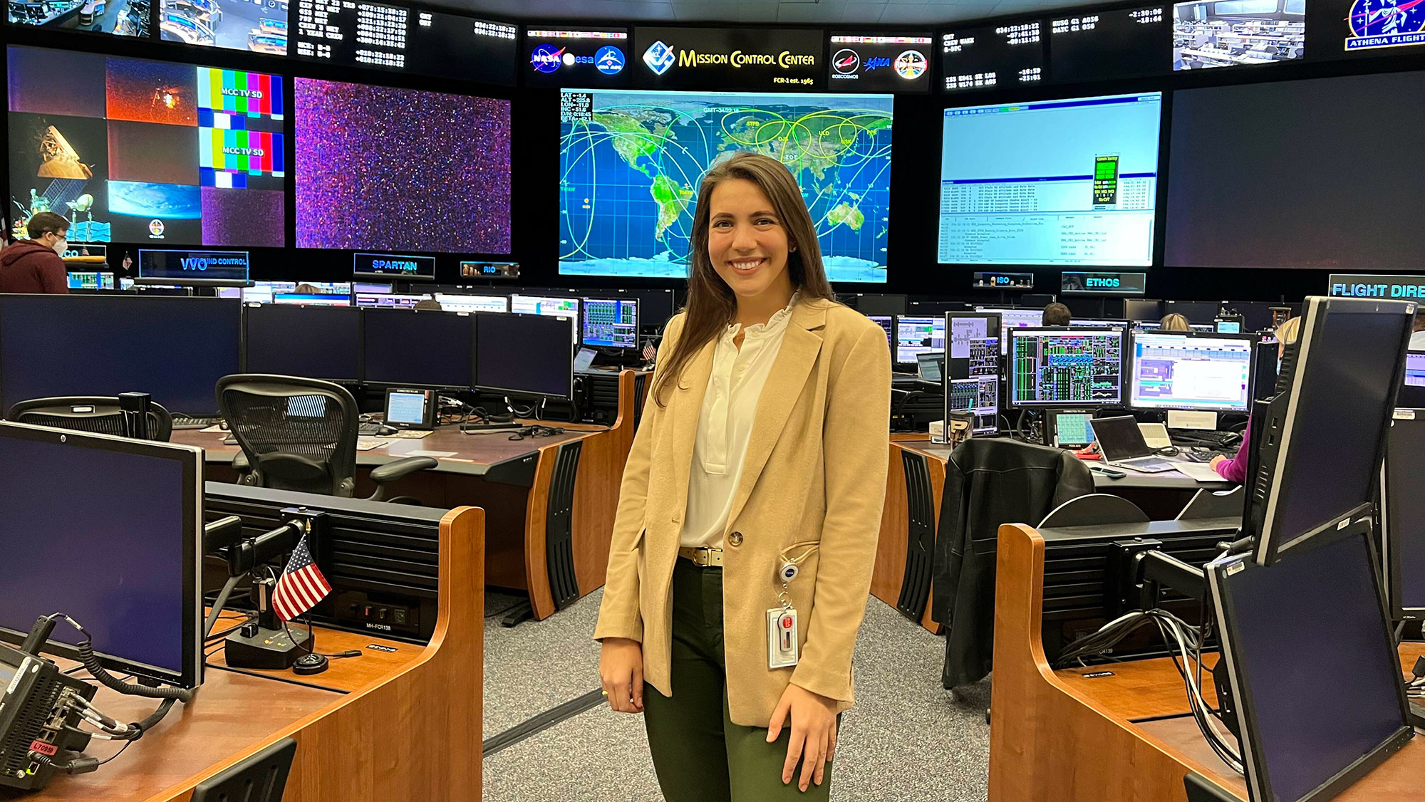 A person standing in the middle of a space mission control room.
