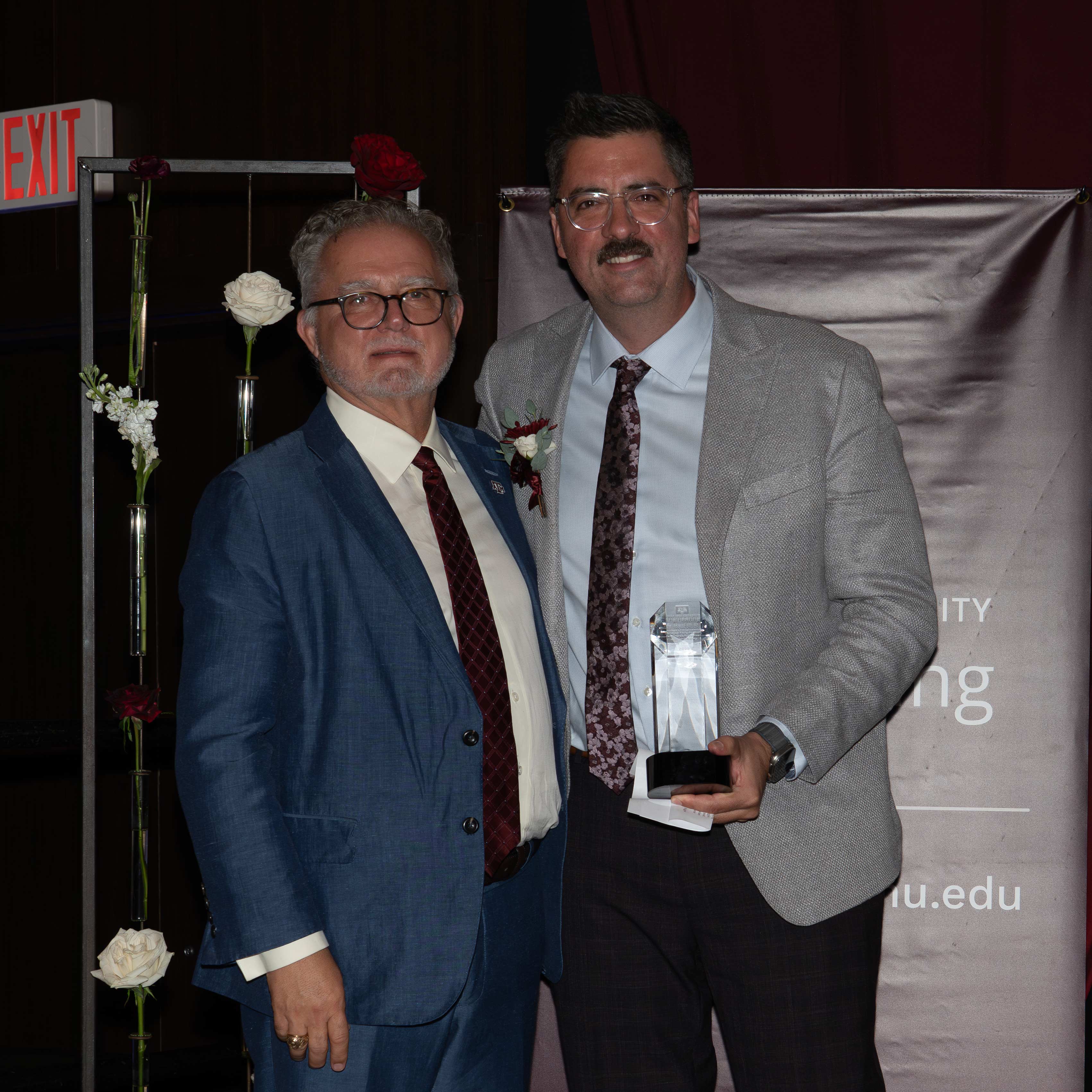 Three men pose with an award.