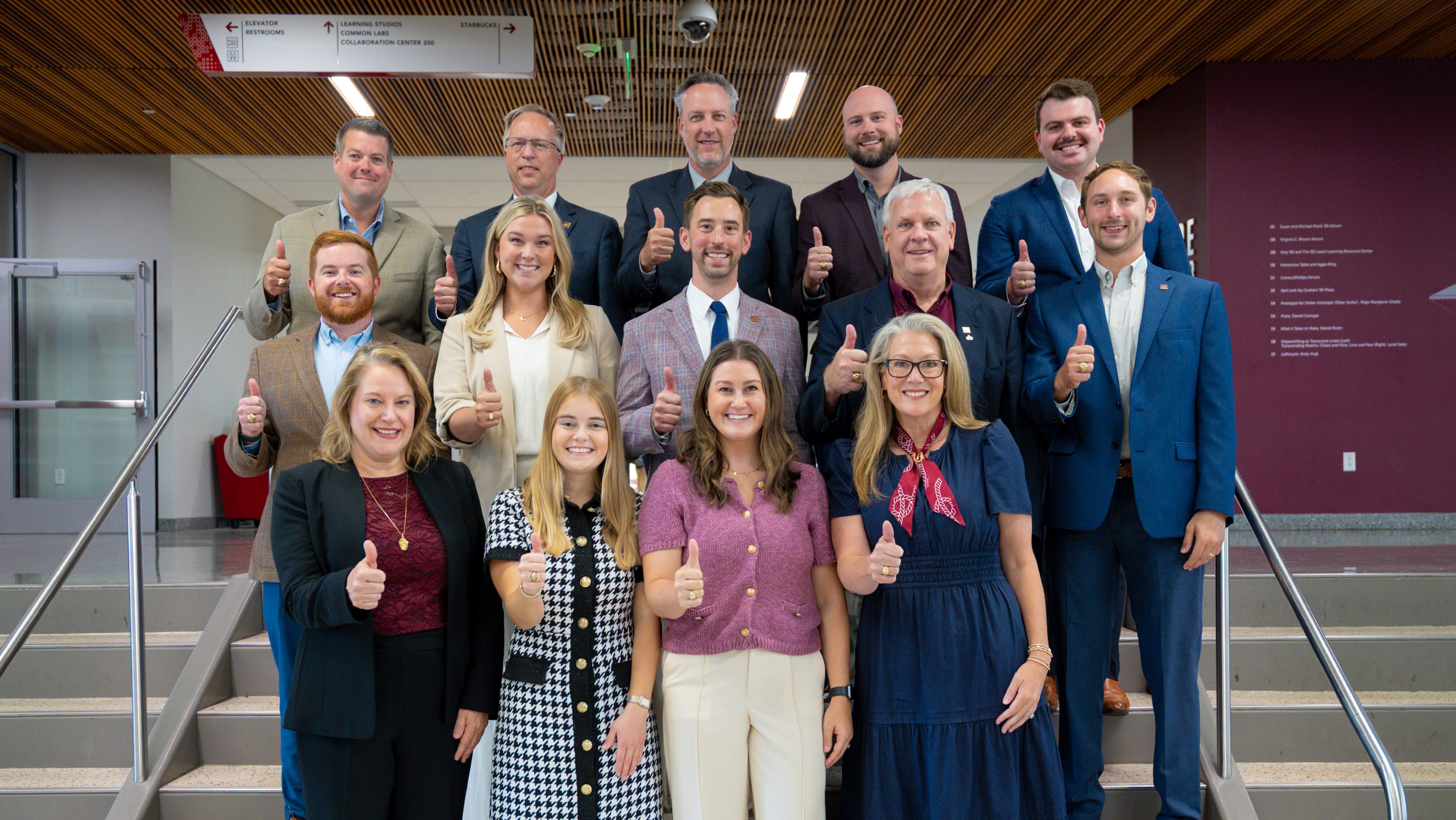 A group of people standing for photo on staircase.