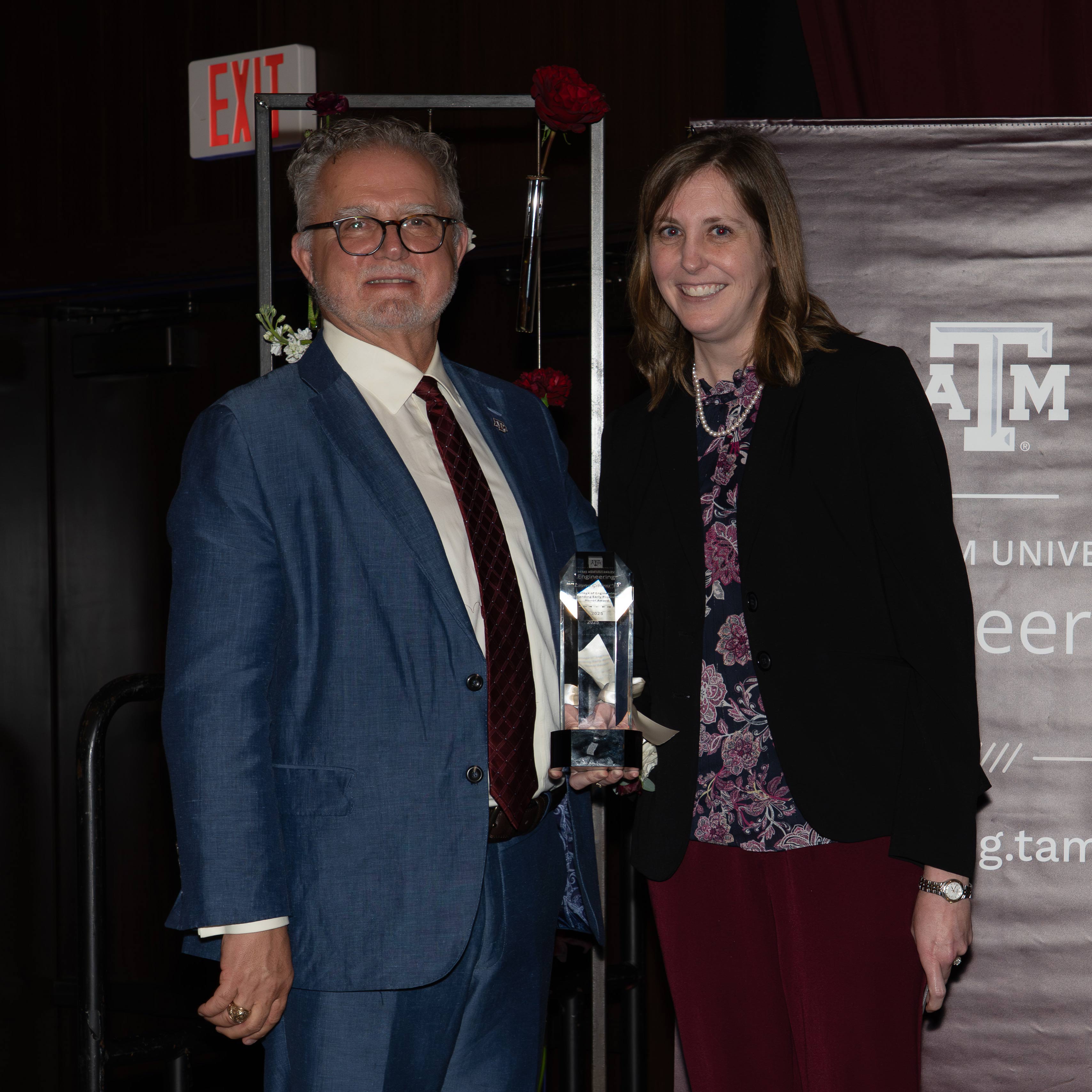 A man and woman pose with an award.