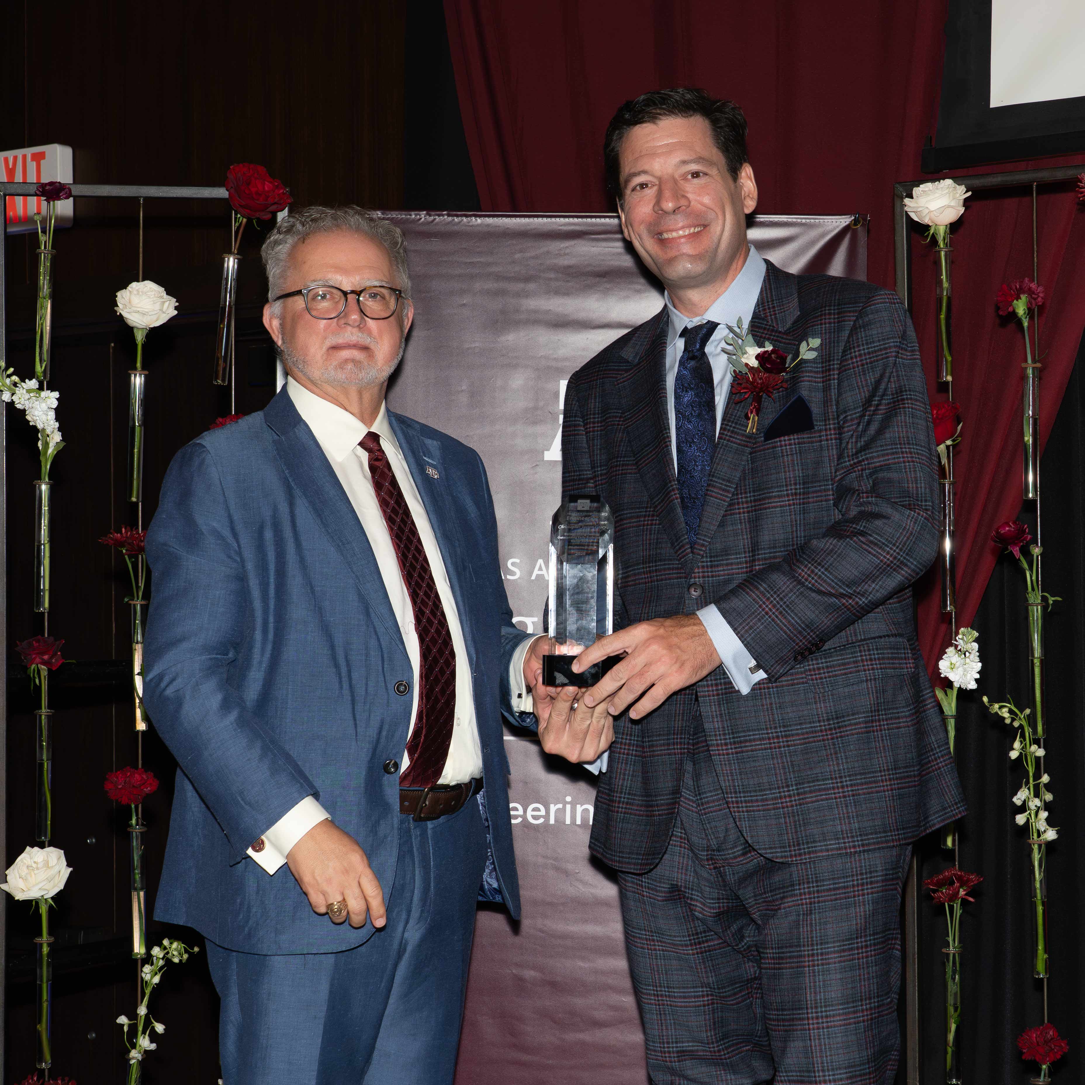 Two men pose with an award.