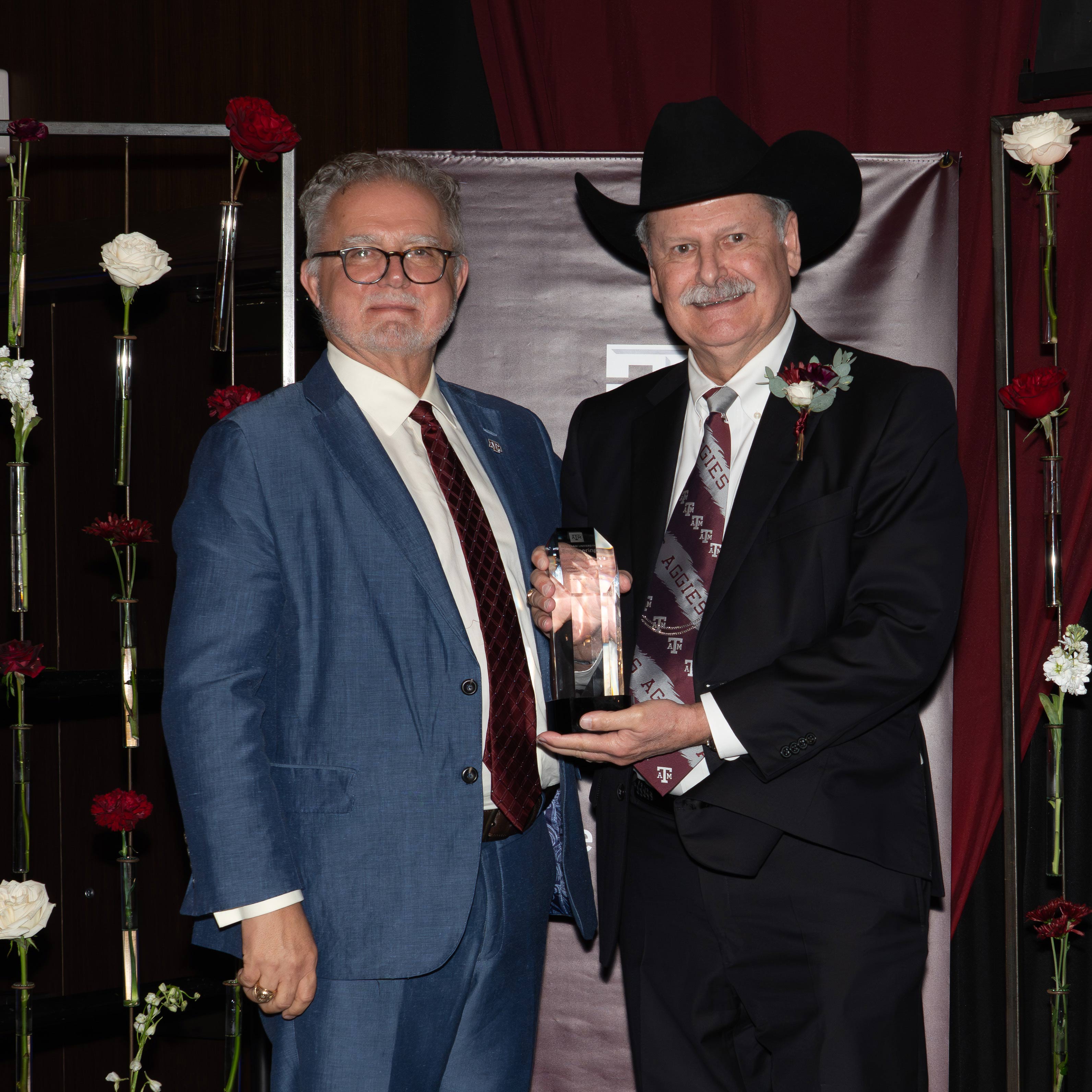 Two men pose with an award.