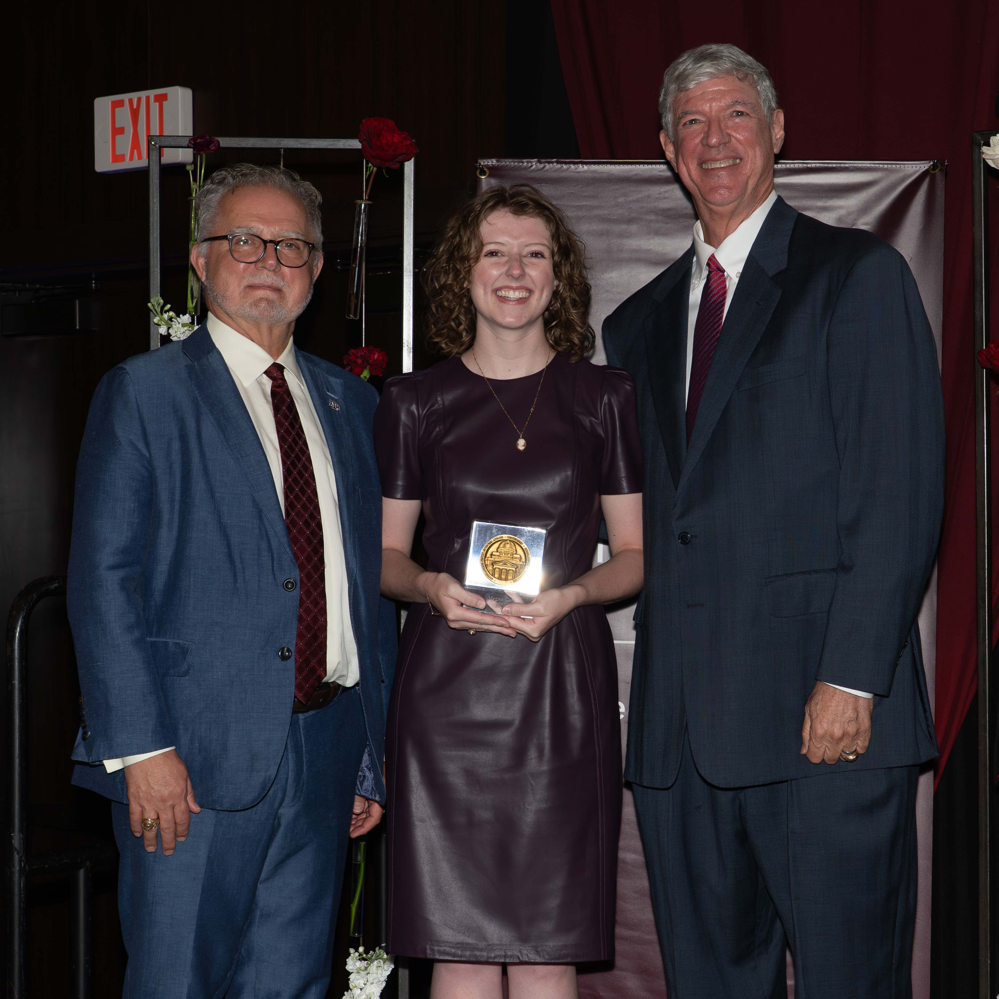 Two men and a woman pose with an award.