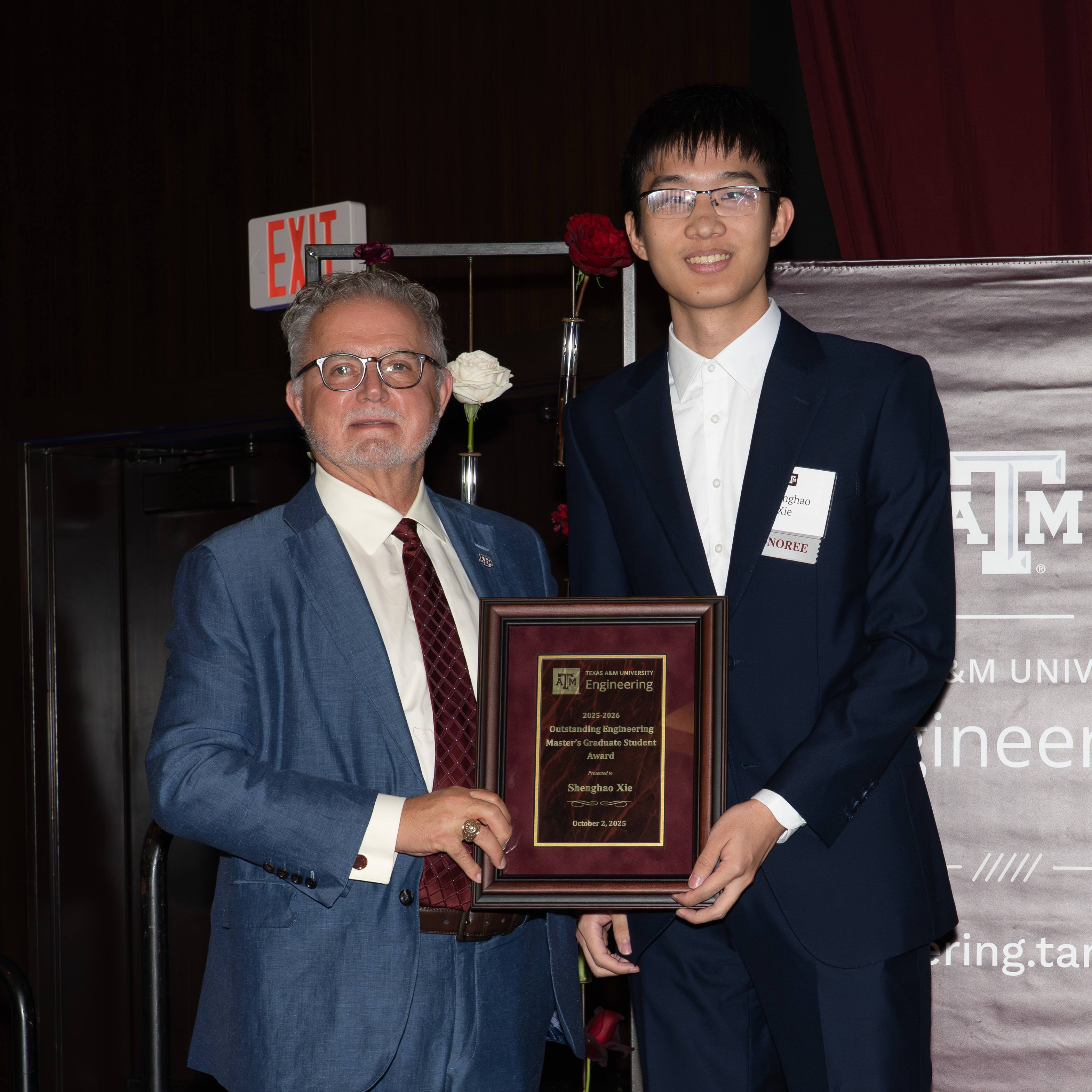 Two men pose with an award.