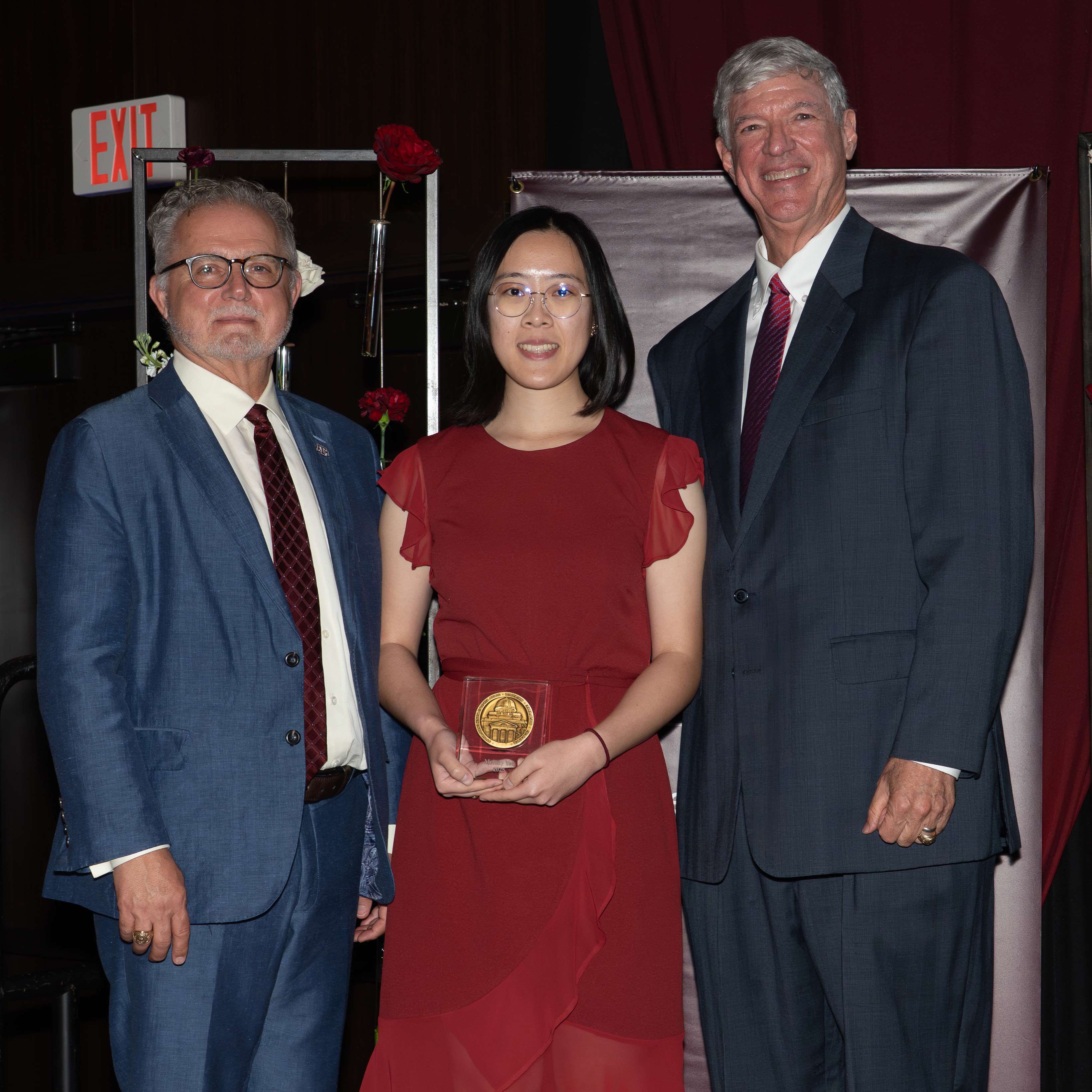 Two men and a woman pose with an award.