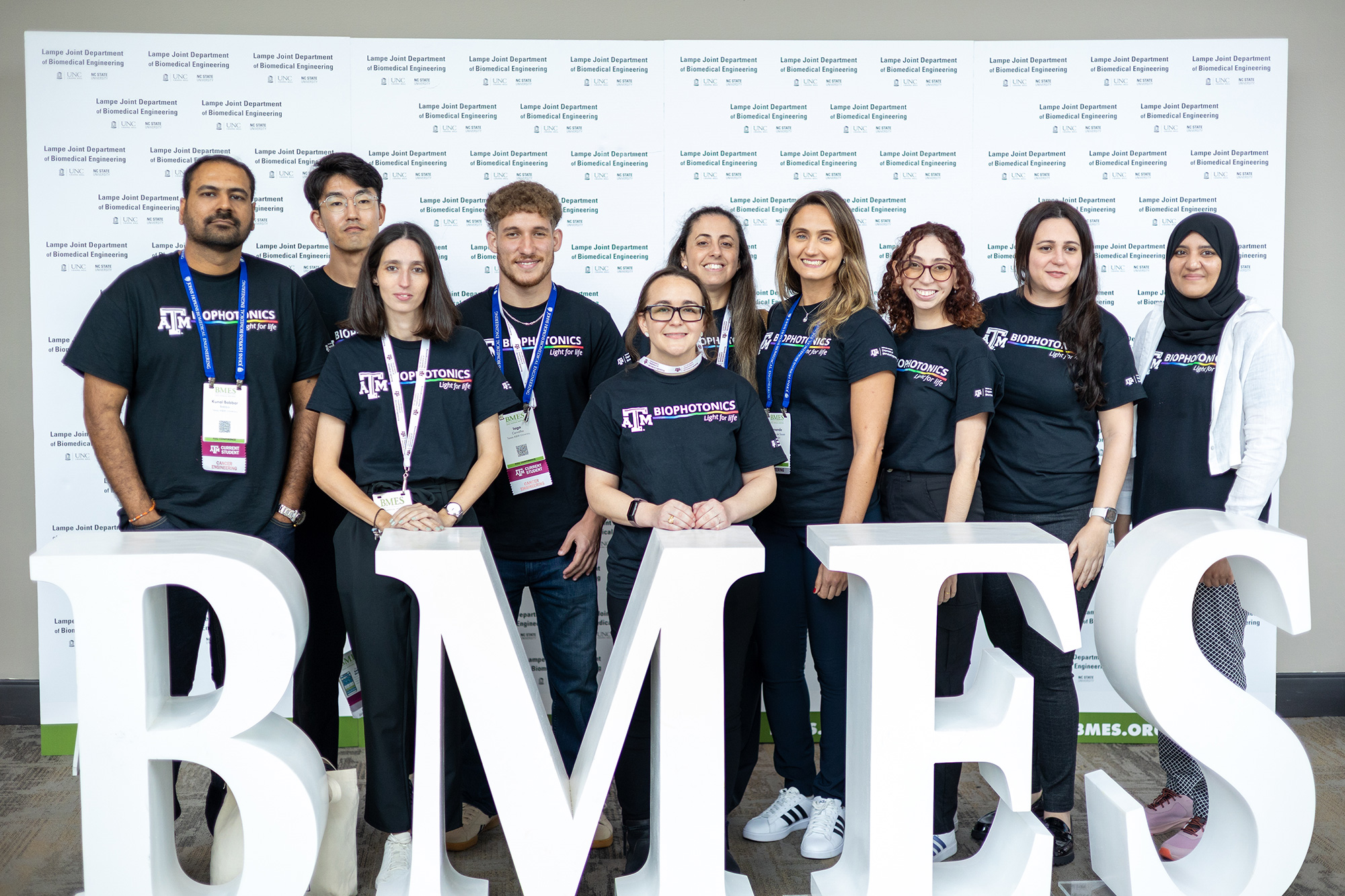 A group of people posing in front of large letters that read BMES.