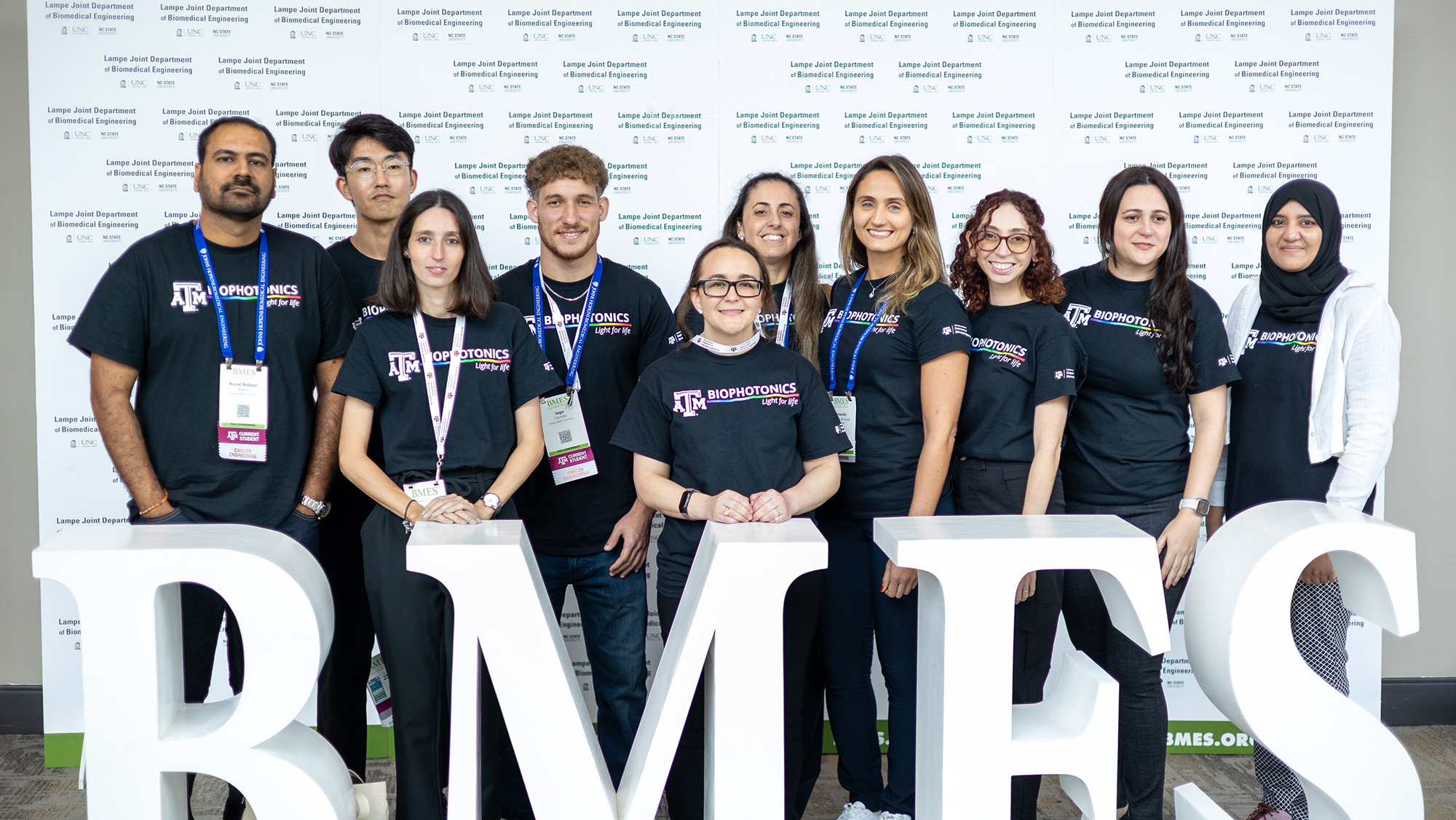 A group of people posing in front of the letters BMES.