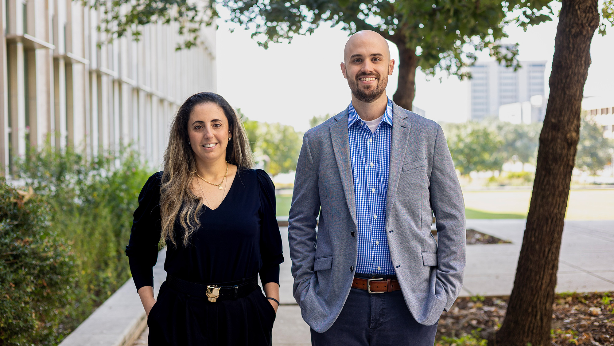 Two people dressed in professional attire standing outside.