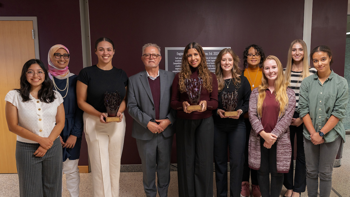 A group photo with three individuals holding trophies.