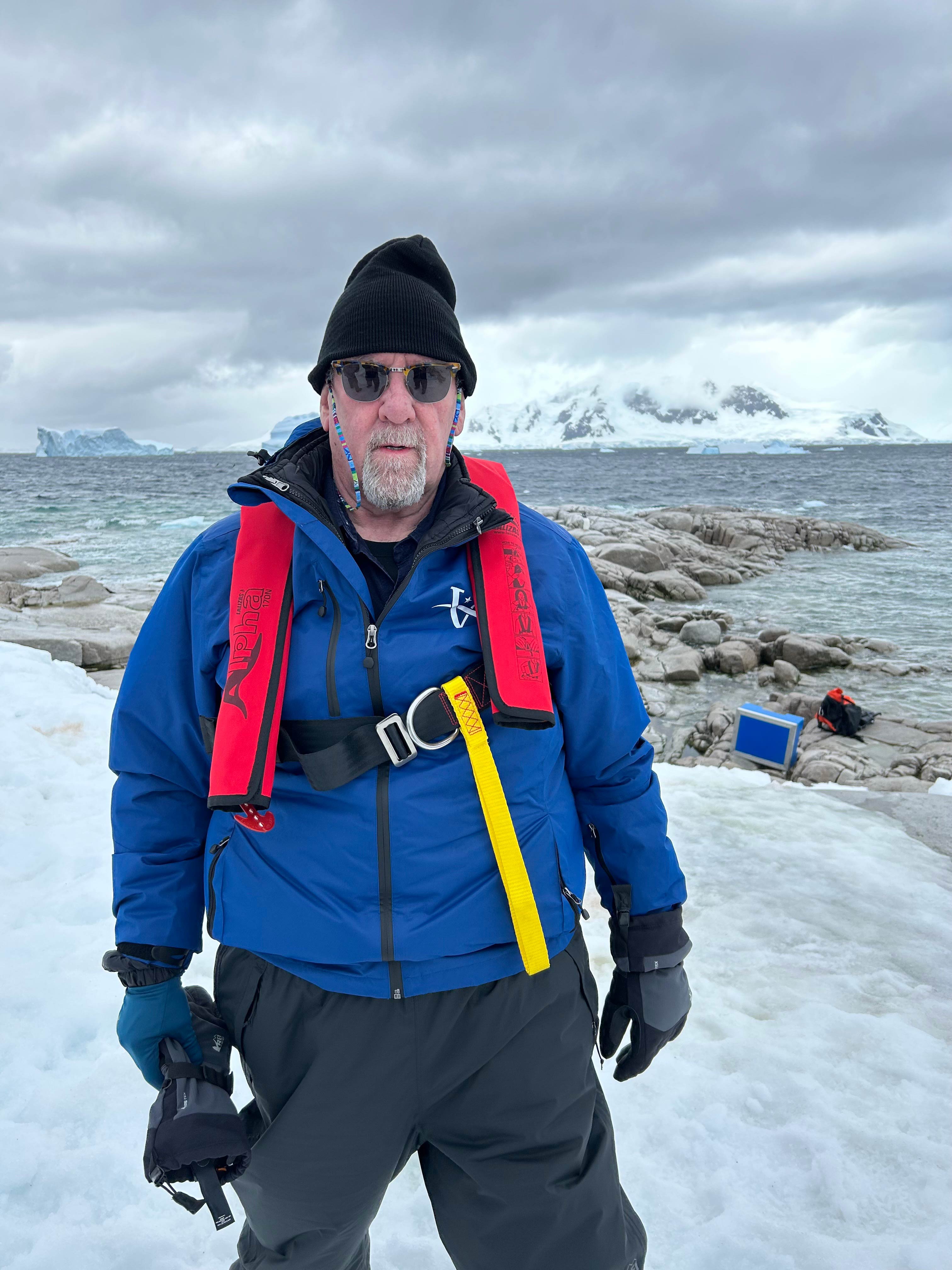 A man standing on ice with mountains in the background.