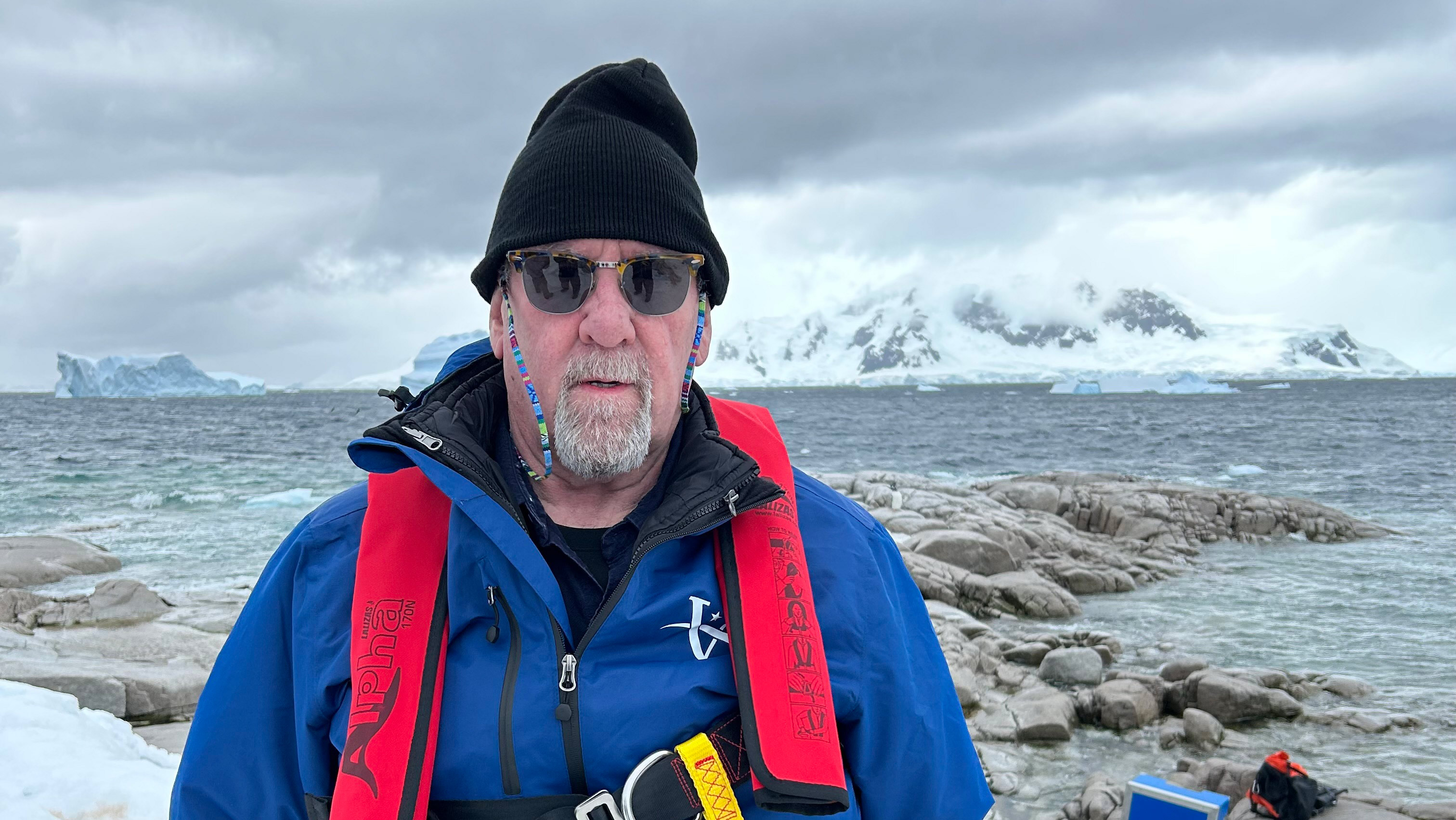 A man standing on ice with mountains in the background.