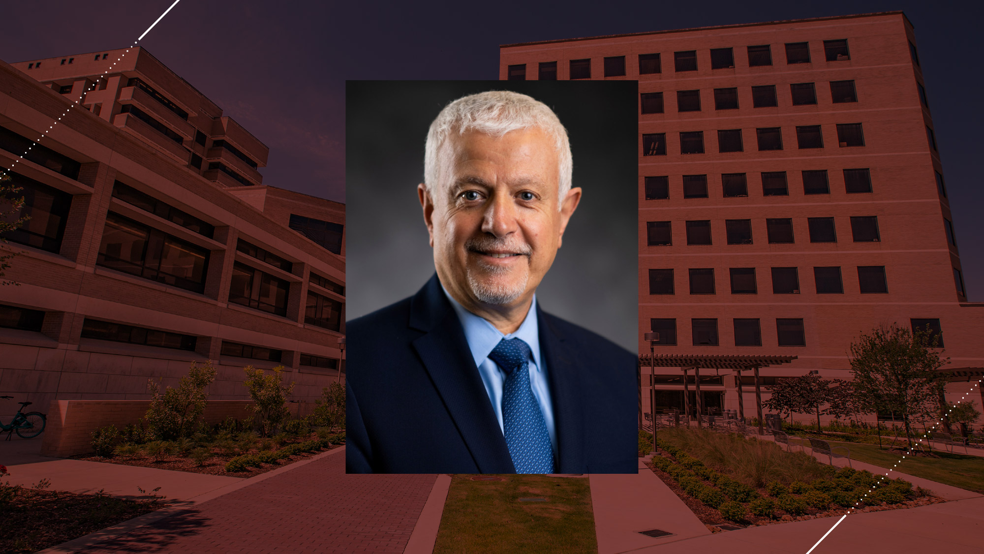 Headshot of a man on a maroon background.