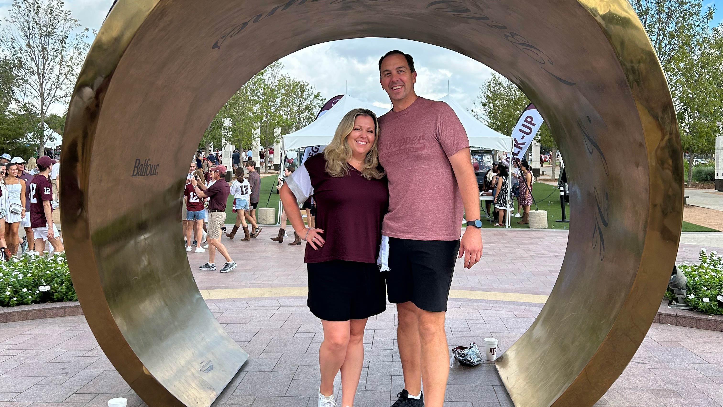 A couple posing in front of a ring statue.