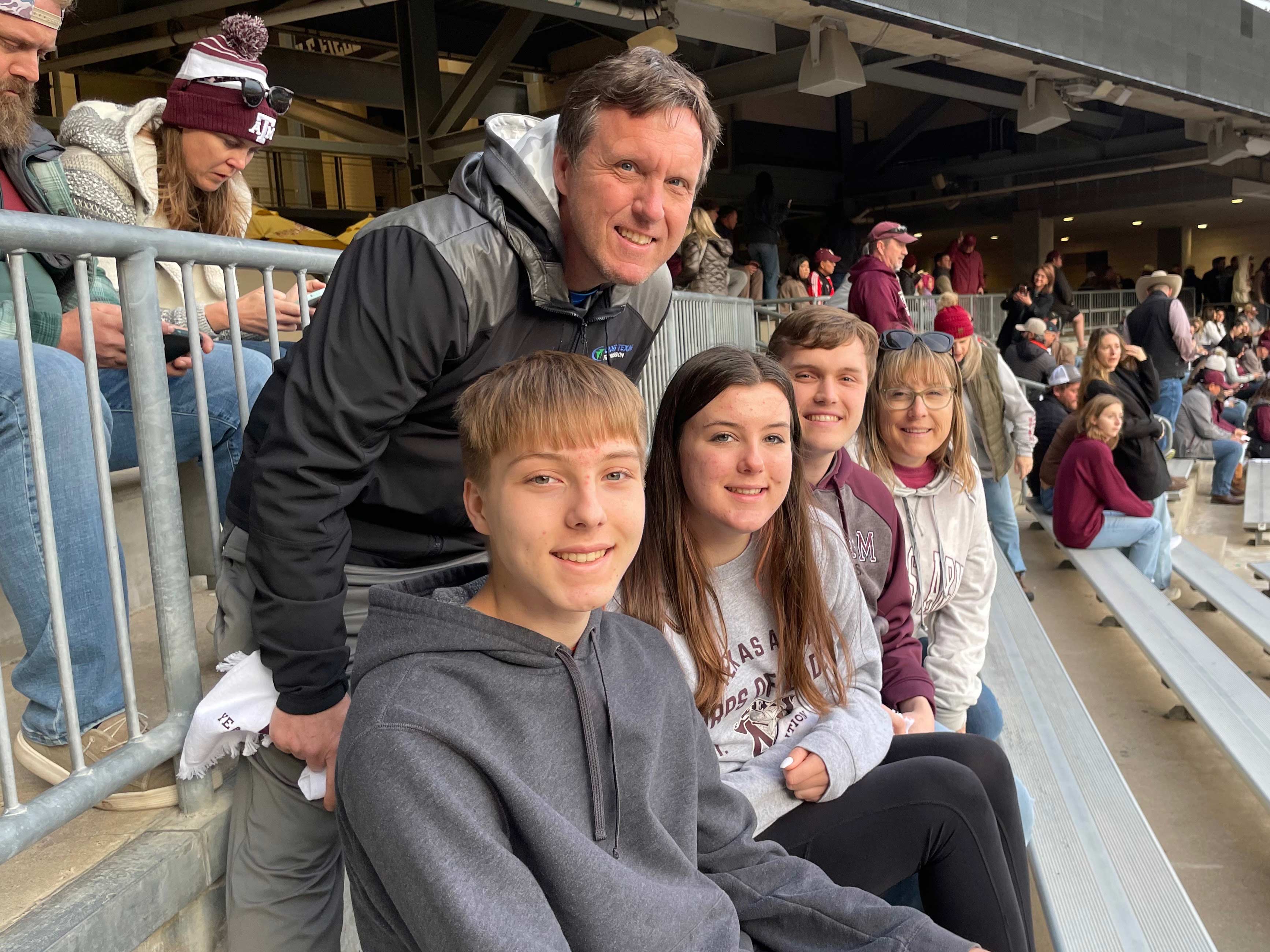 A family posing for a photo on some bleachers.