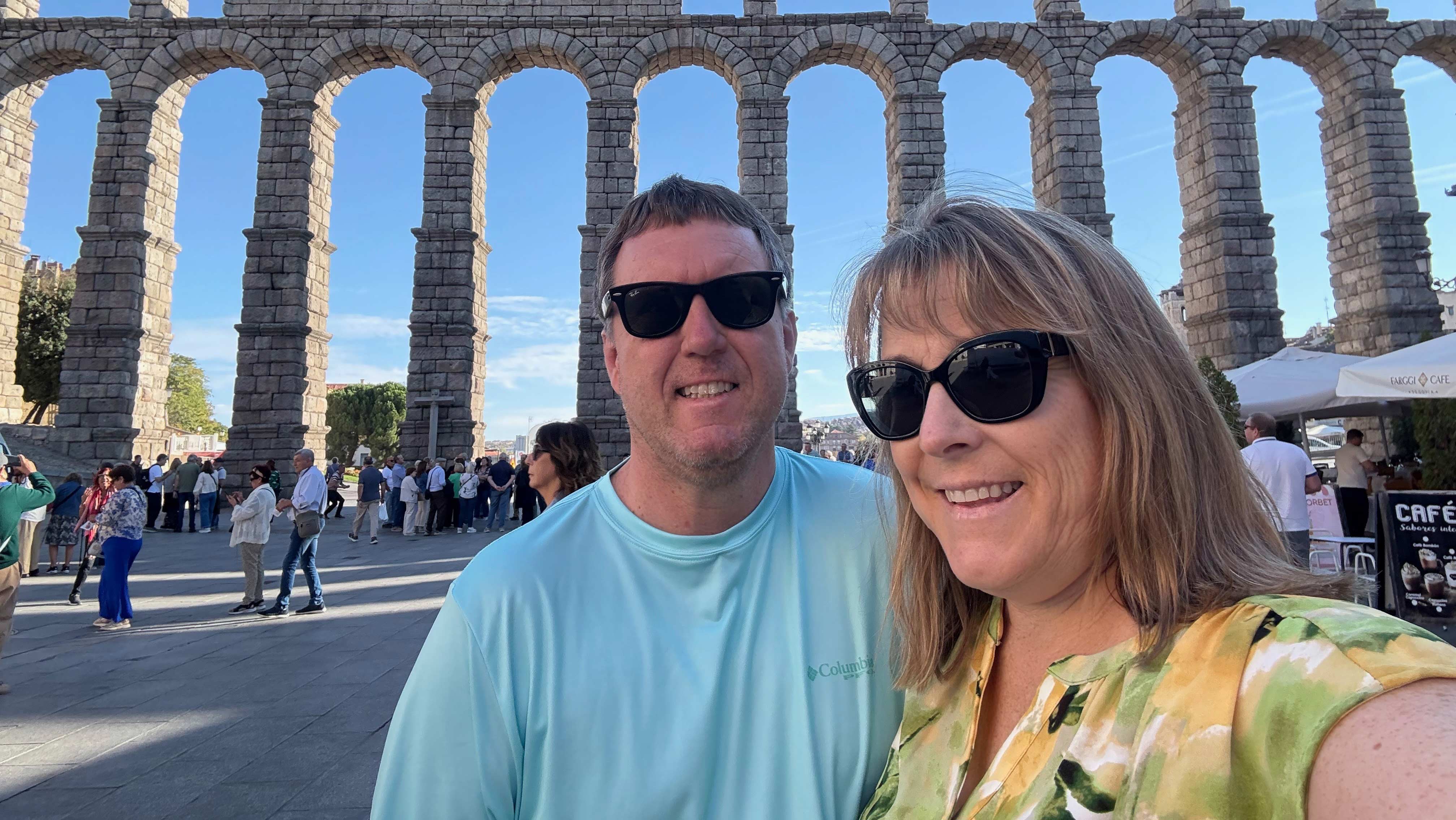 A couple posing for a photo in front of arches. 