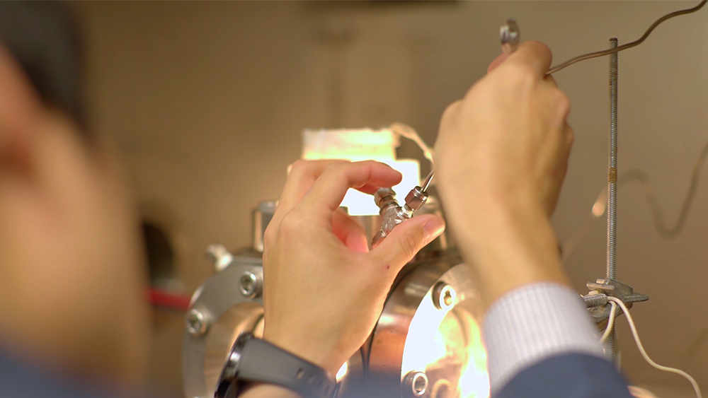 closeup of graduate petroleum engineering student's hands shown adjusting top fitting on gas hydrate investigation chamber