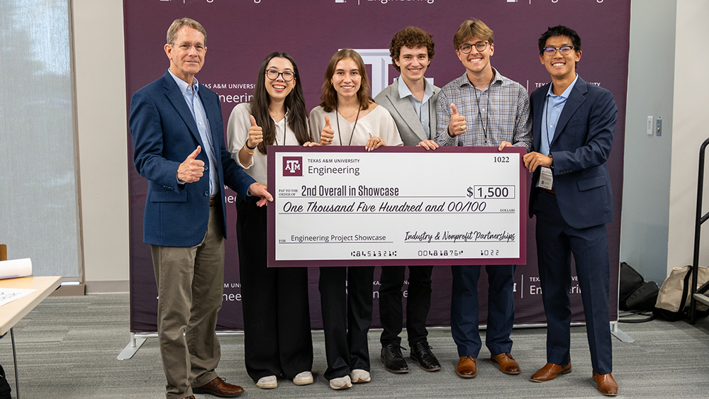 Students and Associate Dean standing with a jumbo check for the second place showcase prize.