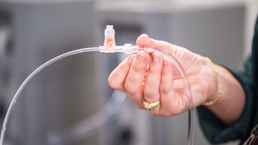 Hand with Aggie ring holding up a catheter.