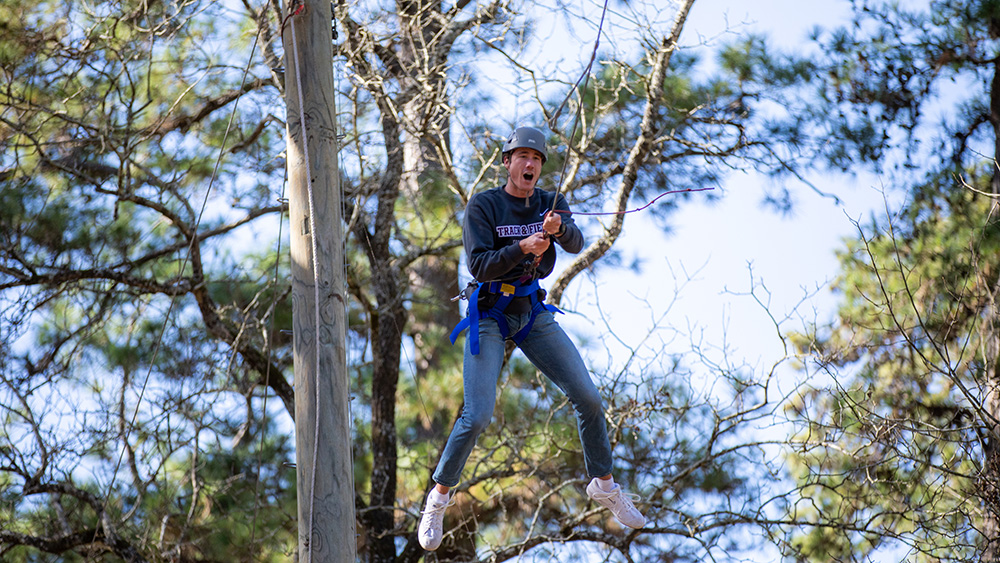 A student flying though the air on a zipline.