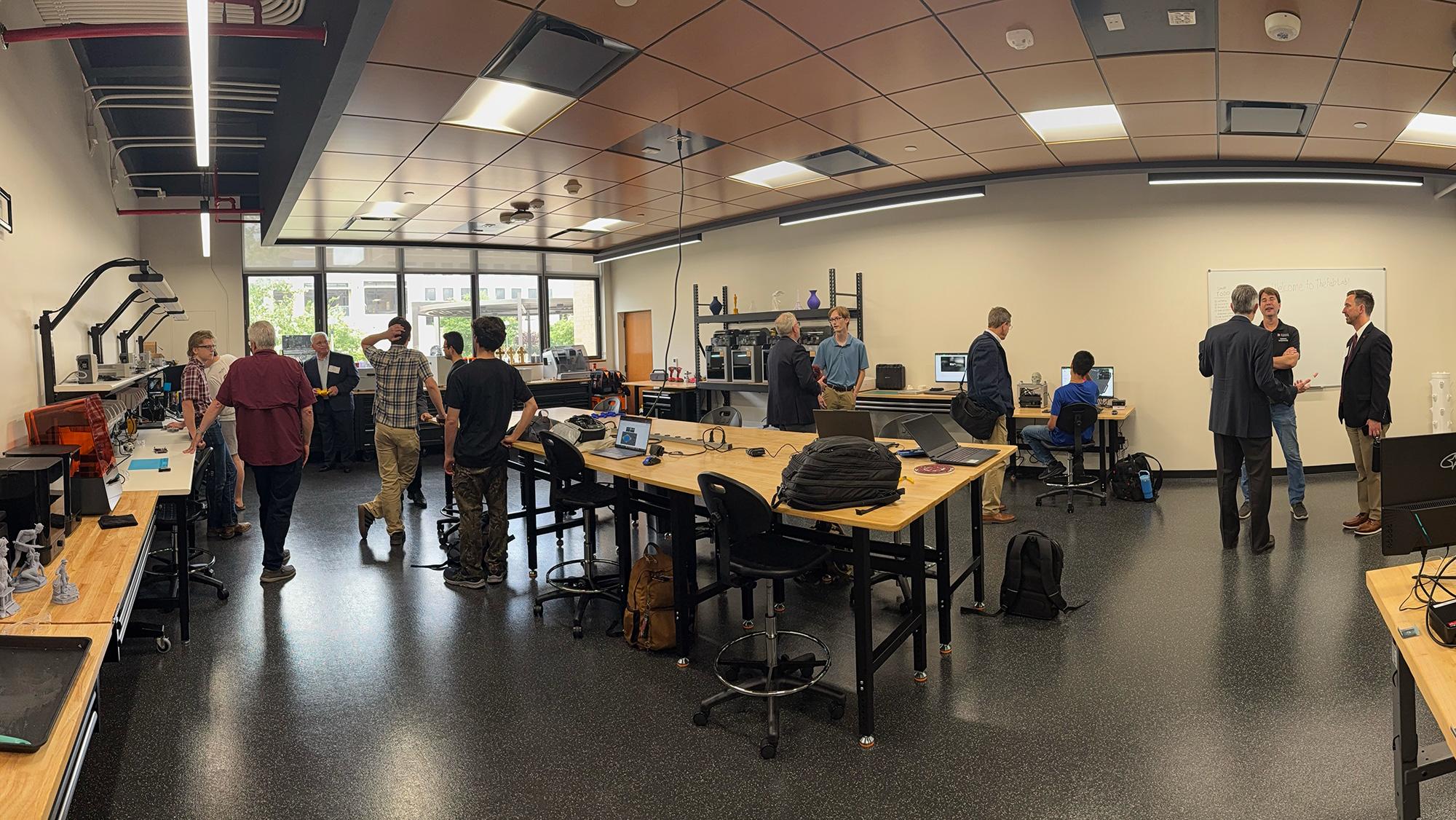 A panoramic view of the Meloy Fab Lab. Several people are throughout the lab talking to each other.